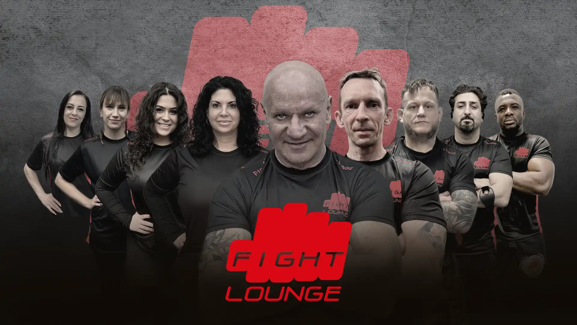 Das Trainer-Team der Fight Lounge: Die Head Coaches und der Kampfsport-Schule für die Standorte Bochum, Dortmund und Hagen posieren vor einem großen roten Faust-Logo auf grauem Hintergrund.